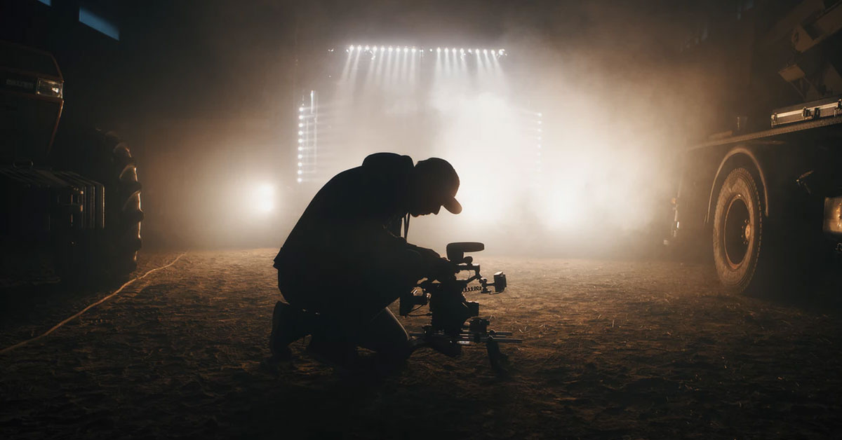 Man with camera filming in dark barn